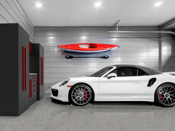 white convertible sports car parked in a brightly lit garage with custom red and gray cabinets and matching gray polyflake floor